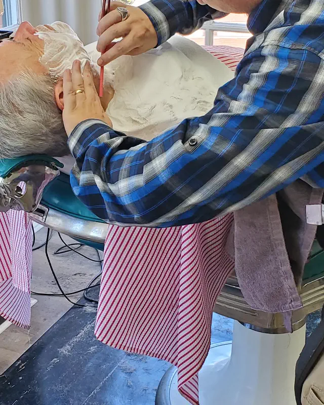 A hot lather straight-razor shave under a red-striped cape